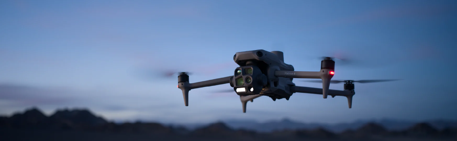 DJI Mavic 4 Pro in flight at dusk over mountain terrain